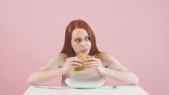 Happy Anorexic Girl Greedily Eating a Burger. Violation of Diet. Anorexia alt