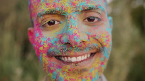 Zoomout Portrait of Joyful Guy Standing Outdoors at Holi Festival Smiling Looking at Camera alt