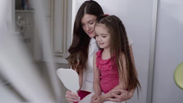 Happy Female Dentist Shows Little Client Helthy Smile at Dental Mirror in Clinic alt