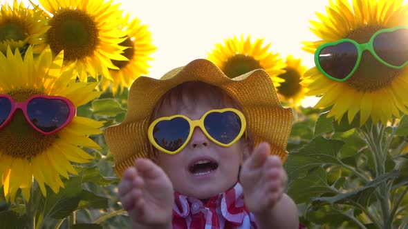 Happy child having fun in spring field of sunflowers