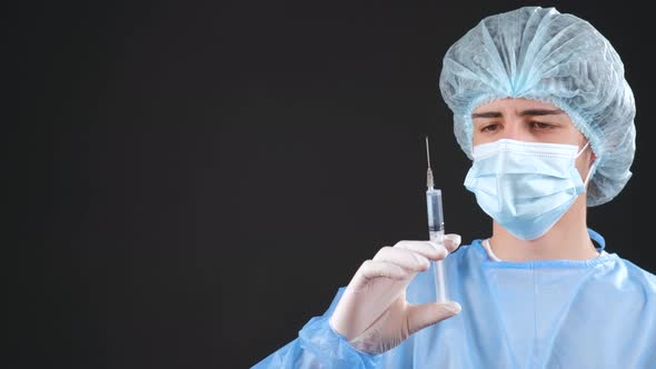 Professional Male Doctor Holds a Syringe with a Vaccine on a Black Background alt