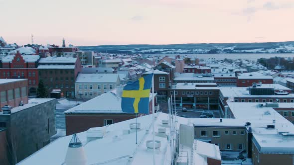Orbiting aerial shot of Swedish flag in Östersund on a fall day alt