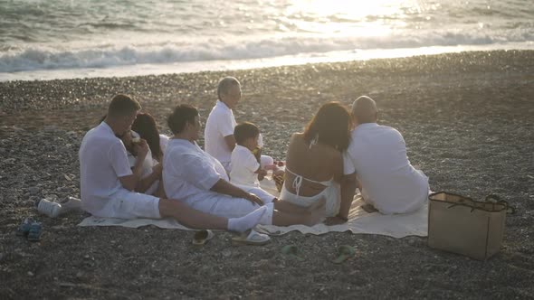 Wide Shot Back View of Relaxed Asian Family Admiring Sunset on Mediterranean Sea Coast with Foamy alt
