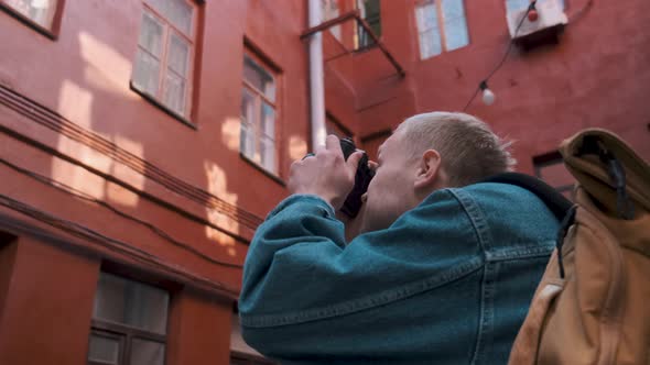 A Young Traveller Takes Pictures of a Red Brick Building in an Old Town alt