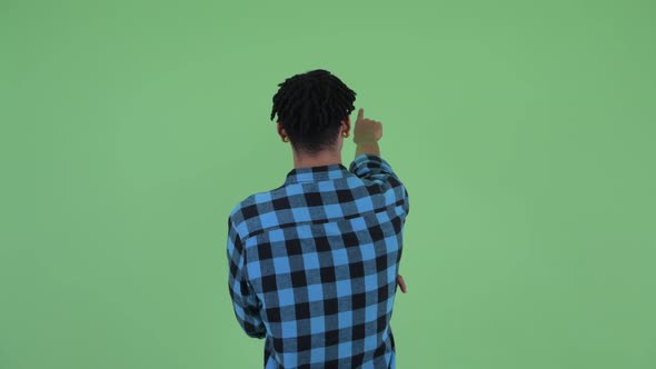 Rear View of Young African Hipster Man Directing and Pointing Finger alt
