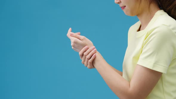 Young Asia girl applying protective cream on hands isolated over blue background.