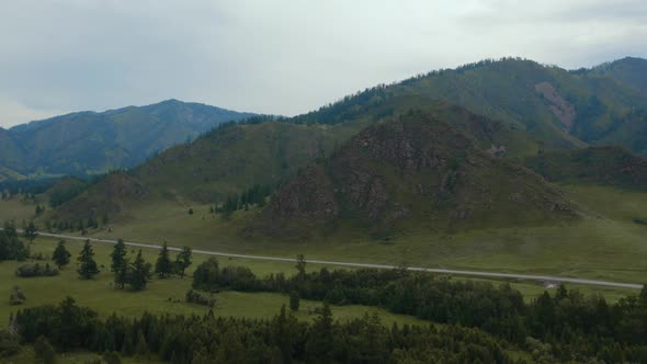 Road between field and mountains in Altai alt