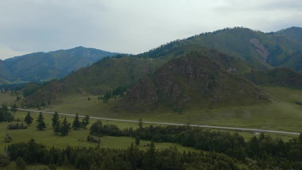 Road between field and mountains in Altai
