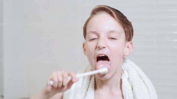 Cute Brunette Boy Brushing His Tongue with a Toothbrush and Gel. Bright Bathroom