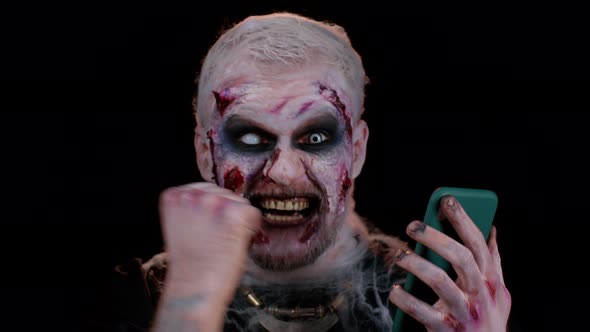 Happy Excited Sinister Man Halloween Zombie Use Smartphone Celebrating Lottery Win Success Luck alt