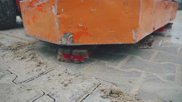 The machine automatically mashes the seams with sand after installing the pavement. Close-up.