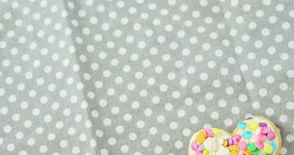 Decorated heart shape cookie against polka dot background alt