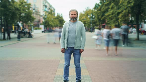 Zoomin Time Lapse Portrait of Serious Mature Man Standing Outside in Street with People Rushing alt