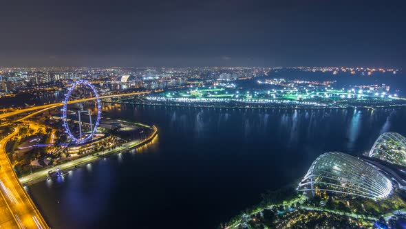 Skyline of Singapore with Famous Singapore Ferries Wheel Night Timelapse alt