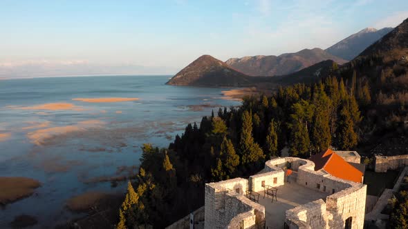 Birds eye view of Besac Fortress situated on hilltop amidst thick pine forest beside vast blue sea. alt