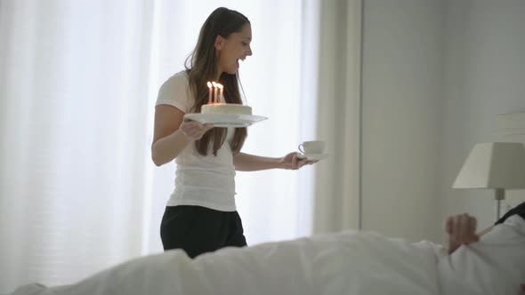 Young Wife Bringing Her Husband Birthday Cake to Bed