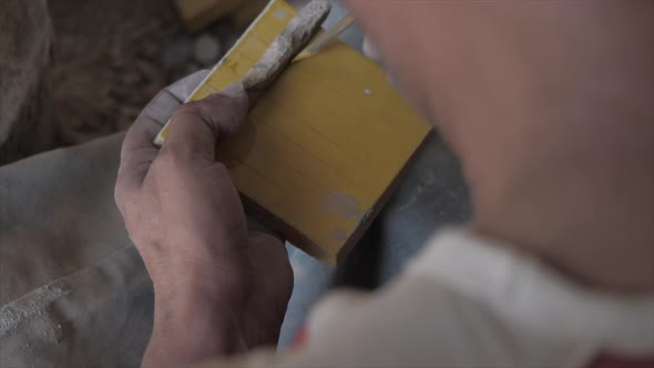 Close up view of a carpenter drawing a piece of wood in his small carpentry workshop.  Handcrafting alt