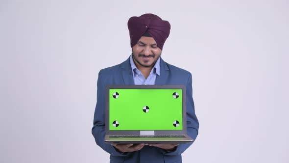 Happy Bearded Indian Sikh Businessman Thinking While Showing Laptop alt