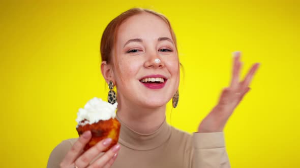 Funny Redhead Young Woman with Green Eyes Putting Muffin Cream on Nose and Smiling at Camera alt