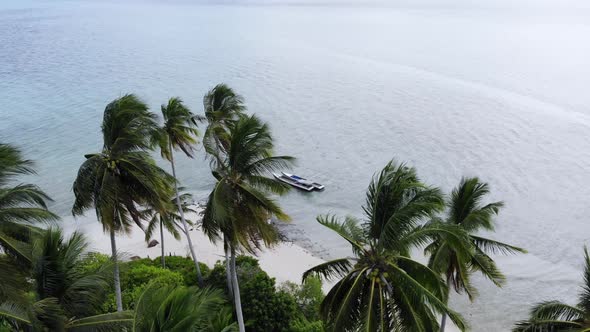 Ungraded cinematic aerial view of a beautiful small island beach in the middle of the ocean