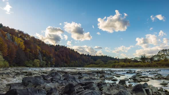 Stone Bank Against Colorful Trees Growing on Hills in Autumn alt