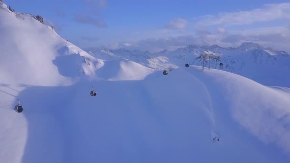 Aerial drone view of a ski gondola lift and mountains at a ski resort alt