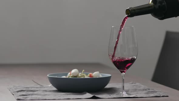 Slow Motion Pour Red Wine Into Wineglass with Bowl of Fettuccine on Background alt