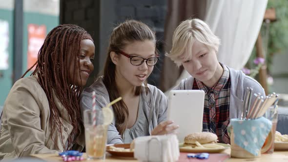 Girls Surfing the Net on Tablet and Having Lunch Together alt