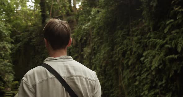 Back View Following a Young Caucasian Man Exploring a Tropical Rainforest in Bali alt