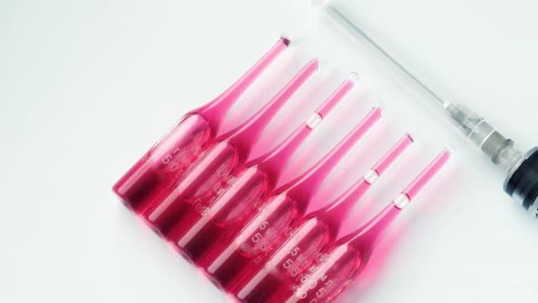 Syringe with Ampoules and Red Medicine Lie on a Pastel Blue Background alt