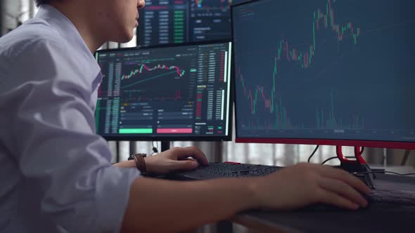 Male Stock Market Broker Looking Analyzing Graphs On Multiple Computer Screens alt