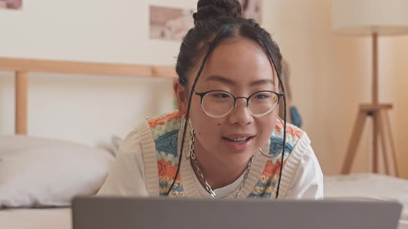 Asian Teenage Girl Texting with Friends on Laptop alt