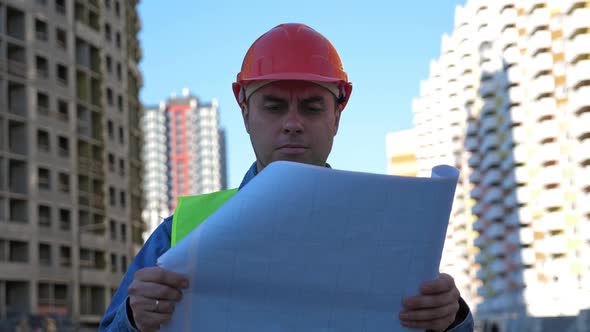 Engineer with Blueprint in Protective Helmet at Construction Site alt