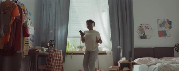 African American Woman in Headphones Dancing in Bedroom alt