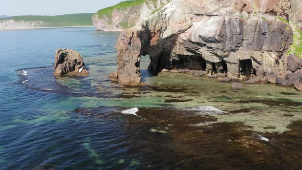 Drone View of a Natural Stone Arch on the Seashore on a Sunny Day alt