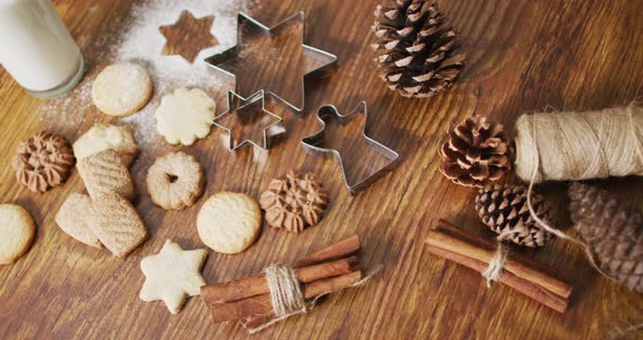 Video of christmas decorations with an assortment of cookies and glass of milk on wooden background alt