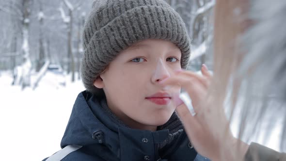 Boy Getting Winter Skin Care From Mom Applying Face Cream alt