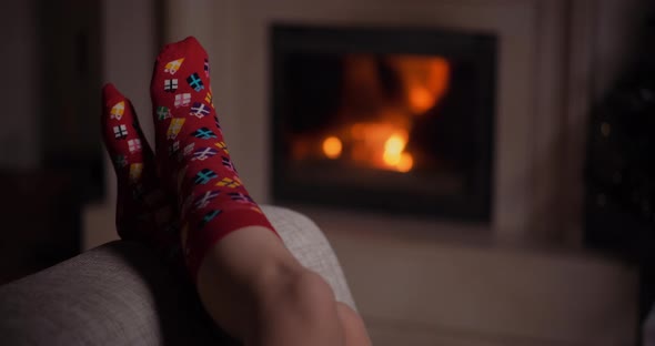 Woman Wearing Warm Wool Socks Lying By the Fireplace at Christmas alt