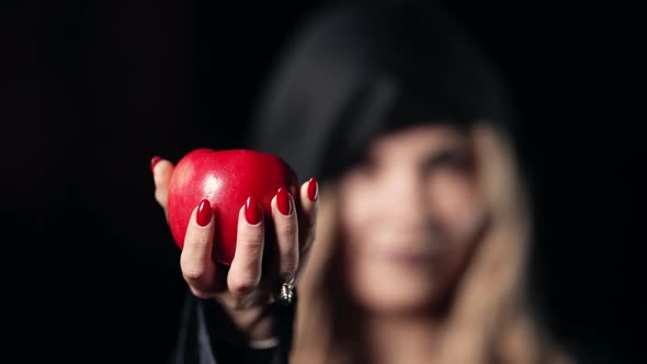 Woman As Witch with an Evil Grin Laugh in Black Offers Red Apple As Symbol of Temptation Poison alt