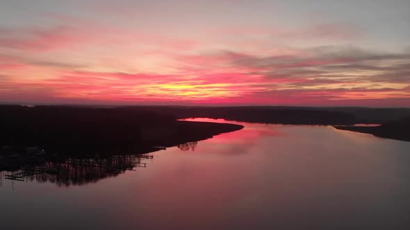 Rotating drone footage of a stunning sunset with a lake and forests on each side. Filmed in realtime alt