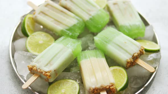 Summer Refreshing Homemade Lime Popsicles with Chipped Ice Over Stone Background