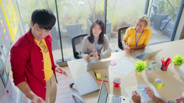 asian male designer present new business plan to his team in office alt