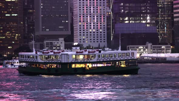 Victoria Harbour in Hong Kong at Night with Star Ferry Sailing by. alt