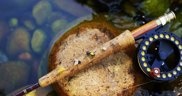 Fly fishing rod, reel and hook on rock alt