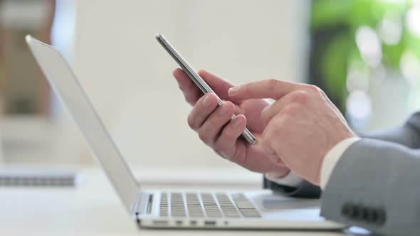 Close Up of Businessman with Laptop Using Smartphone alt