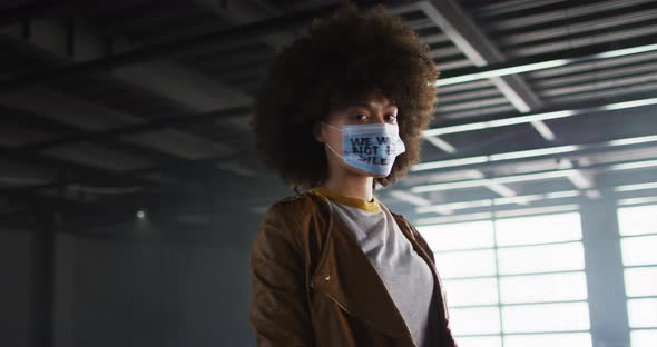 Portrait of african american woman wearing protest face mask in empty parking garage alt