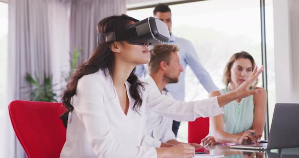 Professional businesswoman using virtual reality headset while sitting in office in slow motion alt