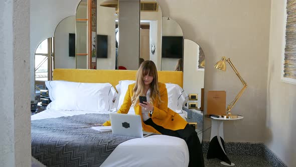 Woman using smart phone and laptop in hotel room, Florence, Tuscany, Italy