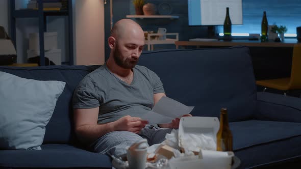 Desperate Man Reading Eviction Notice in Letter Ripping Warning Document alt
