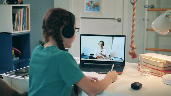 Teenage Girl Is Taking Notes After Her Teacher During Online Class alt